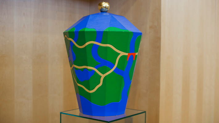 The ballot box is used when a vote on the Speaker is held by secret ballot. The theme is clear blue, green and yellow colours which may be said to represent a Swedish landscape with water, land and roads.  