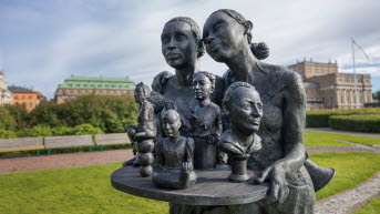 The work of art from the front, with two women carrying a tray with the busts of the first five women in the Riksdag.