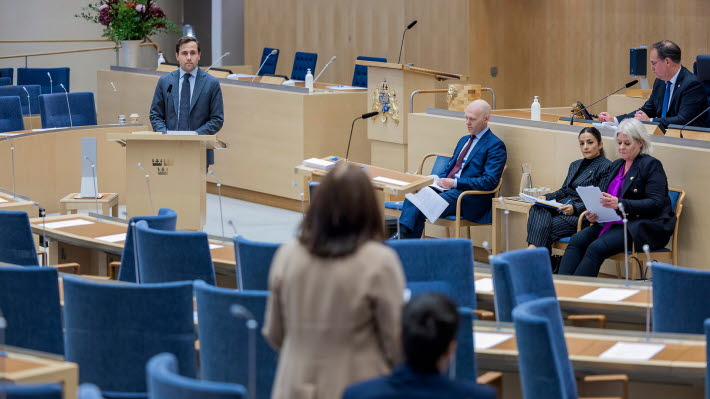 Question Time in the Chamber. A member of the Riksdag stands at his desk and puts a question to one of the ministers who is sitting on the platform.