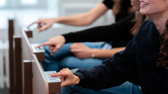 Tre personer trycker på knappar som de har framför sig.